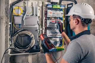 Electrician testing a distribution panel with a multimeter in Dubai
