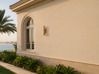 Smooth cream exterior render finish on a villa wall with brushed brass sconce