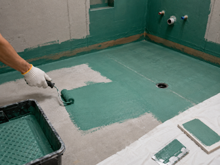 DM-spec liquid waterproofing membrane being rolled onto a shower substrate with mesh joint