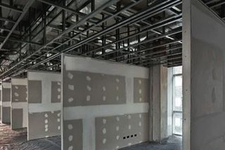Gypsum board cladding fixed to the metal stud frame mid-install, before plaster taping