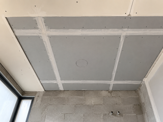Cement-board wet-area ceiling above a villa shower zone with screws and mesh-taped joints visible